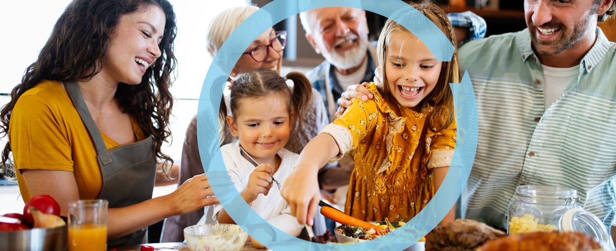 family gathers around kitchen while cooking and tasting holiday foods.