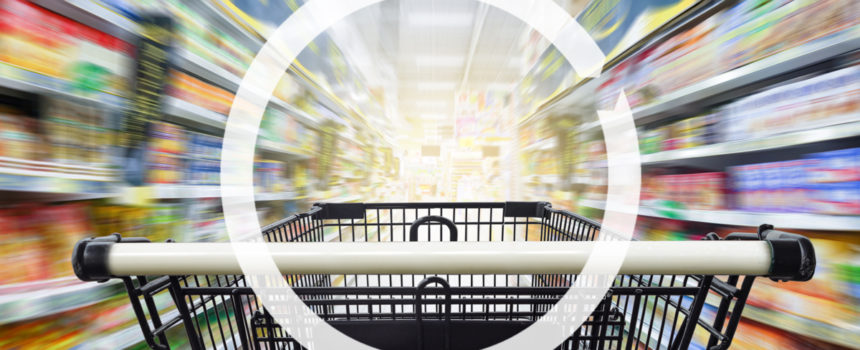 Black grocery cart with white handles in the grocery store with blurred aisles and shelves.