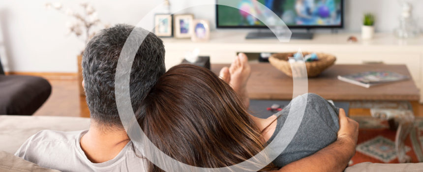 Couple on couch watching TV in living room.